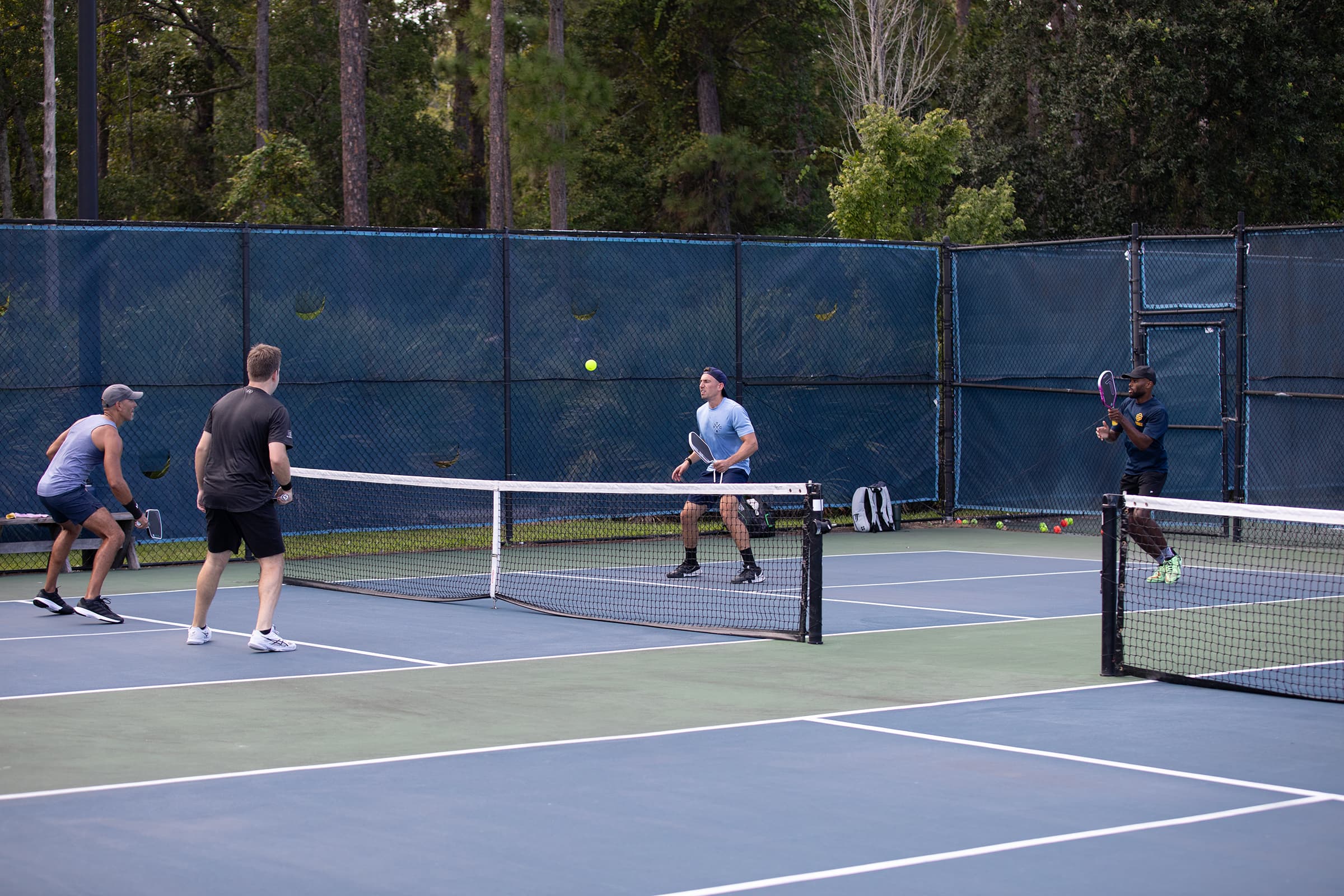 Four Palm Volley players mid-rally at the net